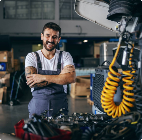 A diesel repair specialist standing and smiling in front of a diesel car engine