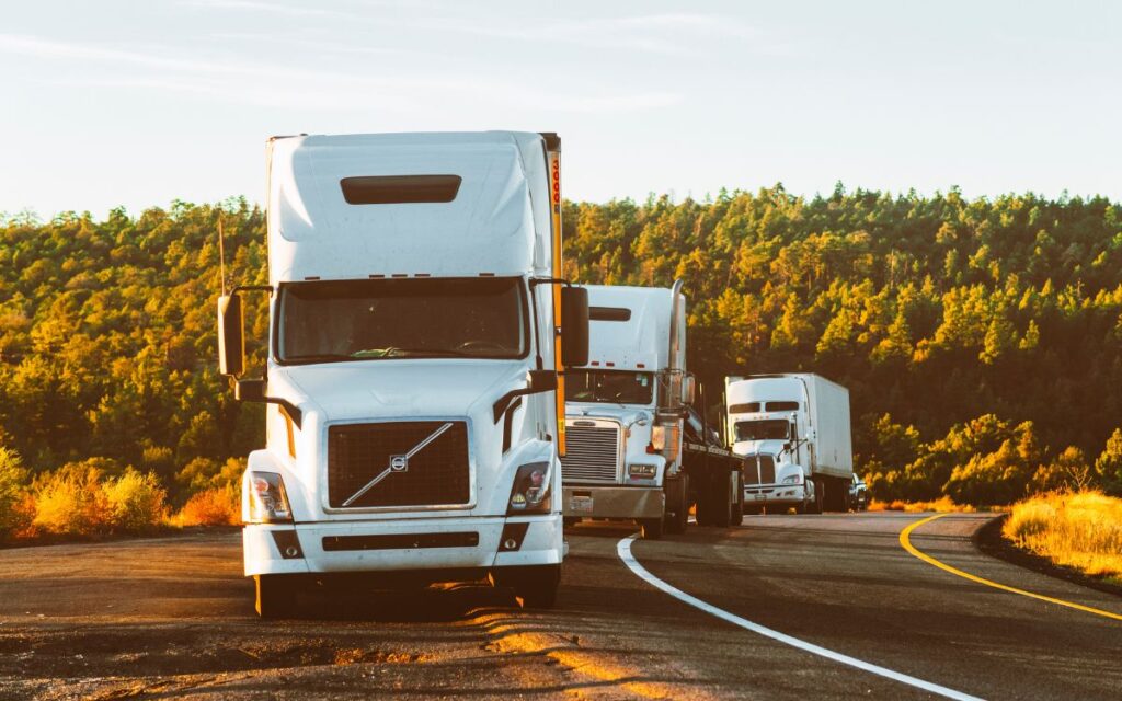 A couple of semi trucks driving down a road