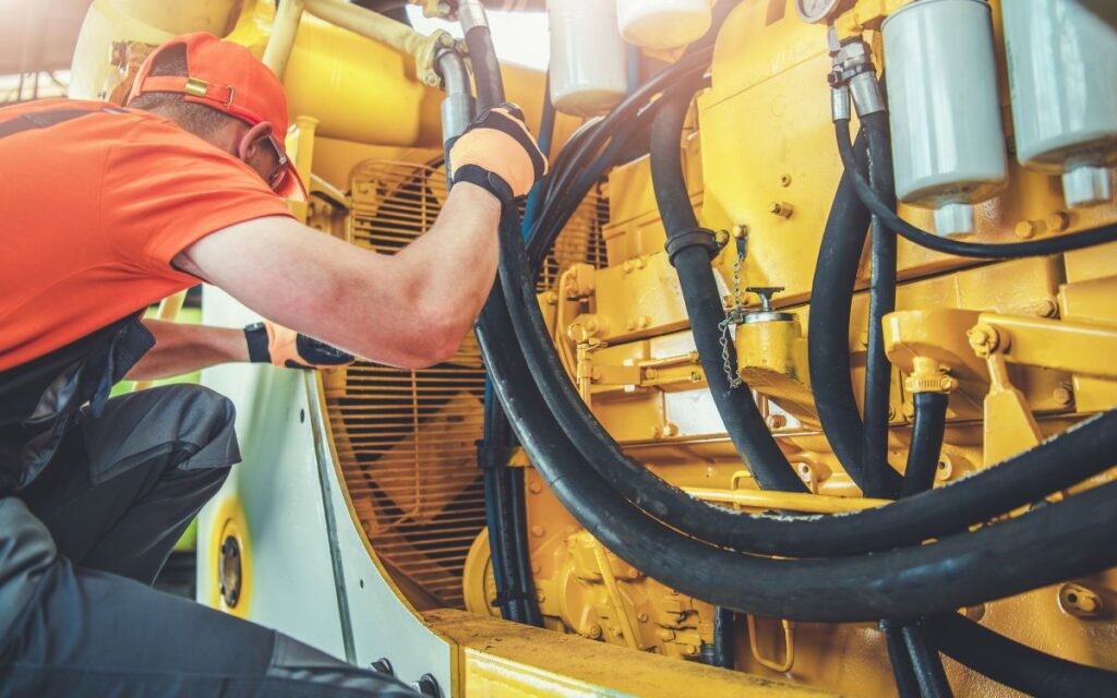 A diesel repair specialist in an orange shirt servicing a machine