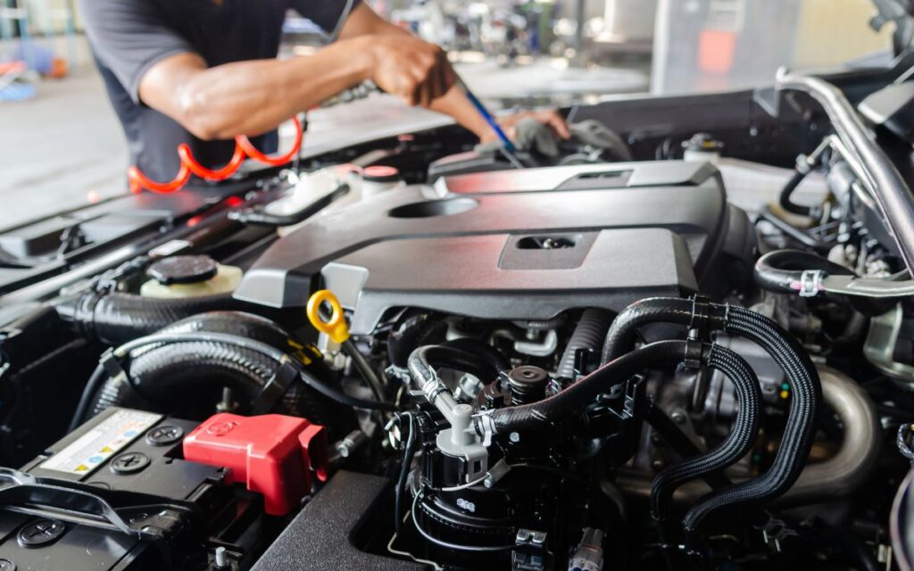 A diesel repair specialist working on a car engine in a garage